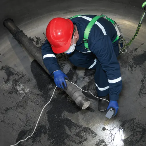 Hygiene technician in full PPE working inside a sewage tank during a cleaning job in Dubai
